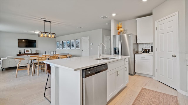 5291 Meredrew Ln, Saint Cloud, FL 34771 - kitchen featuring stainless steel appliances, a sink, open floor plan, a kitchen island with sink, and white cabinets