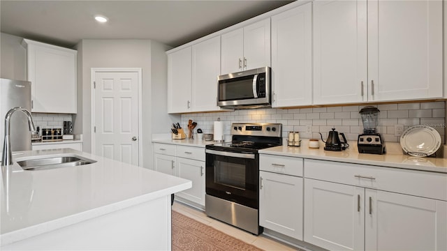 5291 Meredrew Ln, Saint Cloud, FL 34771 - kitchen featuring appliances with stainless steel finishes, a sink, backsplash, light countertops, and white cabinets