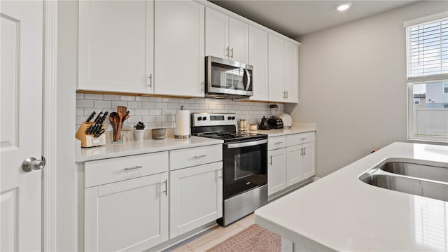5291 Meredrew Ln, Saint Cloud, FL 34771 - kitchen featuring stainless steel appliances, decorative backsplash, white cabinets, light countertops, and recessed lighting