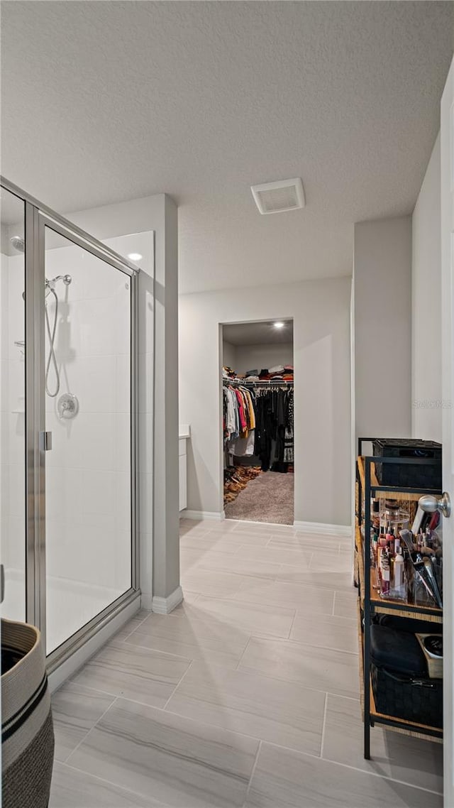 5291 Meredrew Ln, Saint Cloud, FL 34771 - bathroom with a walk in closet, a stall shower, a textured ceiling, and baseboards
