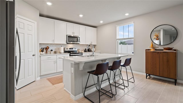5291 Meredrew Ln, Saint Cloud, FL 34771 - kitchen featuring appliances with stainless steel finishes, a sink, a breakfast bar area, decorative backsplash, and light countertops