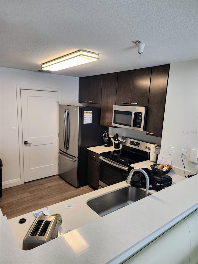 14501 Grove Resort Ave Unit 3737, Winter Garden, FL 34787 - kitchen featuring appliances with stainless steel finishes, a sink, light wood finished floors, light countertops, and a textured ceiling
