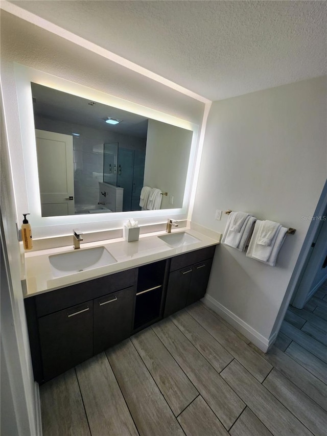 14501 Grove Resort Ave Unit 3737, Winter Garden, FL 34787 - bathroom featuring double vanity, wood finish floors, a shower, a textured ceiling, and baseboards