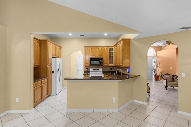 2888 Middleton Cir, Kissimmee, FL 34743 - kitchen with black microwave, stove, white fridge with ice dispenser, arched walkways, and a peninsula