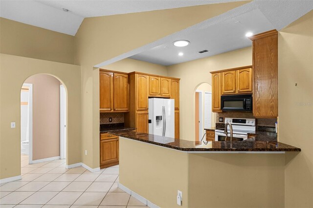 2888 Middleton Cir, Kissimmee, FL 34743 - kitchen featuring white appliances, arched walkways, a peninsula, tasteful backsplash, and dark stone countertops
