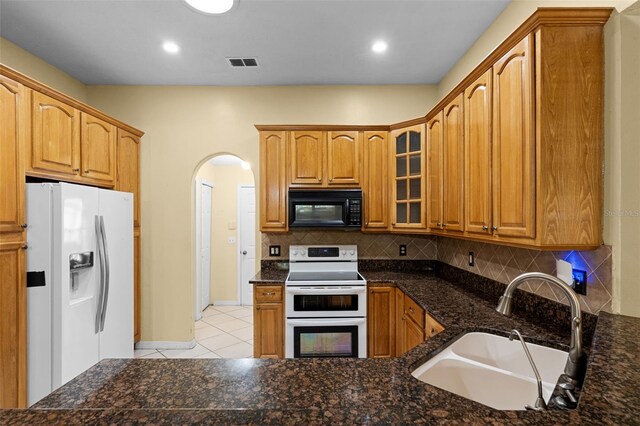 2888 Middleton Cir, Kissimmee, FL 34743 - kitchen featuring white appliances, a sink, arched walkways, light tile patterned floors, and glass insert cabinets