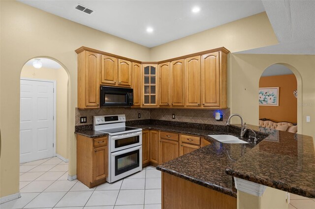 2888 Middleton Cir, Kissimmee, FL 34743 - kitchen featuring range with two ovens, black microwave, arched walkways, a sink, and a peninsula