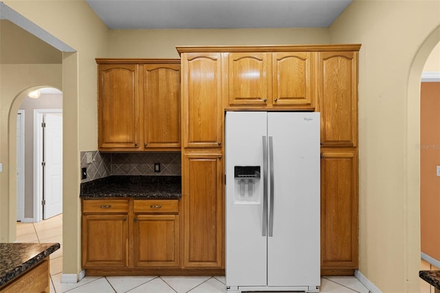 2888 Middleton Cir, Kissimmee, FL 34743 - kitchen featuring white refrigerator with ice dispenser, arched walkways, light tile patterned flooring, and decorative backsplash