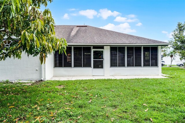 2888 Middleton Cir, Kissimmee, FL 34743 - back of property featuring a sunroom, roof with shingles, a yard, and stucco siding