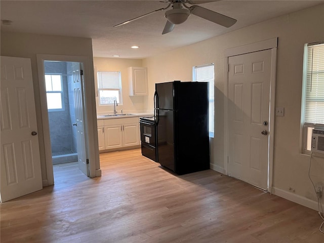 1834 28th Ave N, Saint Petersburg, FL 33713 - kitchen with black appliances, a sink, white cabinets, a ceiling fan, and light wood-style flooring