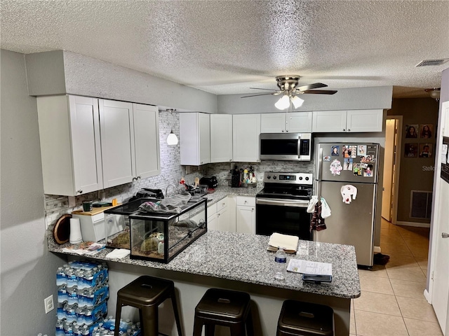 2 Clear Pl, Ocala, FL 34472 - kitchen with stainless steel appliances, a peninsula, a ceiling fan, white cabinets, and a kitchen bar