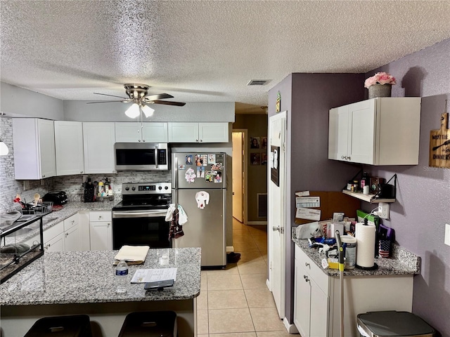 2 Clear Pl, Ocala, FL 34472 - kitchen featuring appliances with stainless steel finishes, a ceiling fan, white cabinets, light stone counters, and a textured ceiling