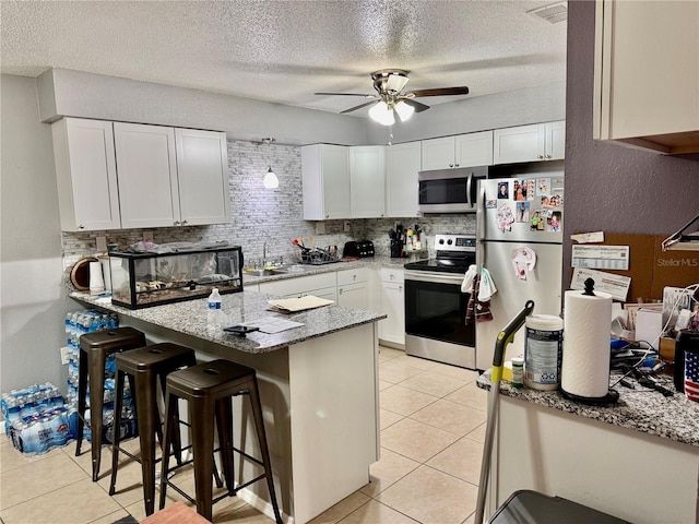 2 Clear Pl, Ocala, FL 34472 - kitchen featuring appliances with stainless steel finishes, a peninsula, decorative backsplash, a ceiling fan, and light stone counters