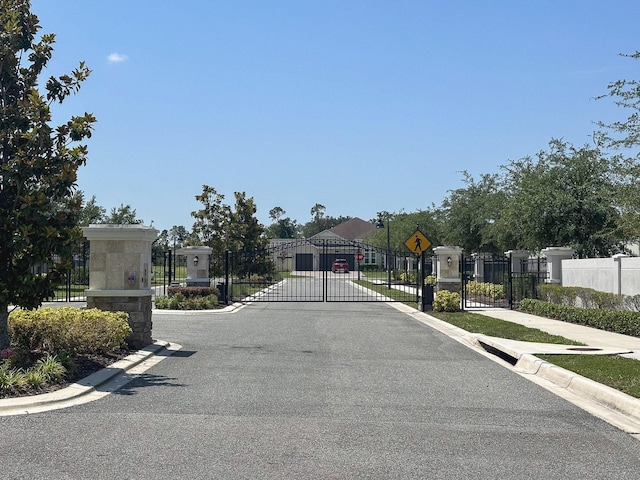 5161 Kingwell Cir, Oviedo, FL 32765 - view of asphalt road with a gate, traffic signs, a gated entry, curbs, and sidewalks