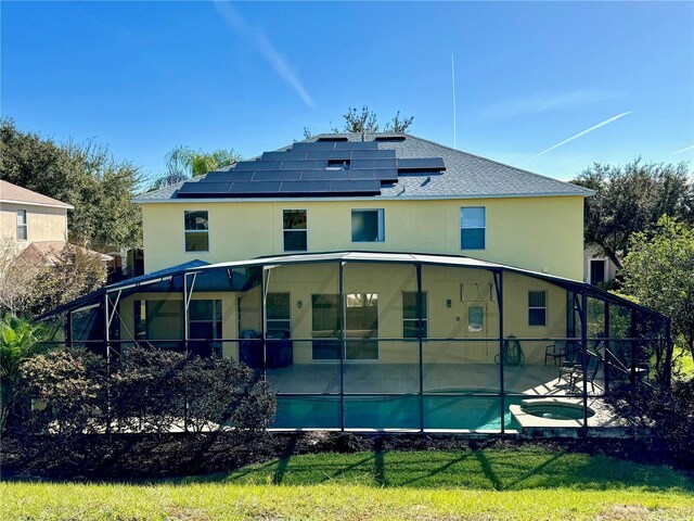 8520 La Isla Dr, Kissimmee, FL 34747 - rear view of house with roof mounted solar panels, a patio, stucco siding, and a pool with connected hot tub