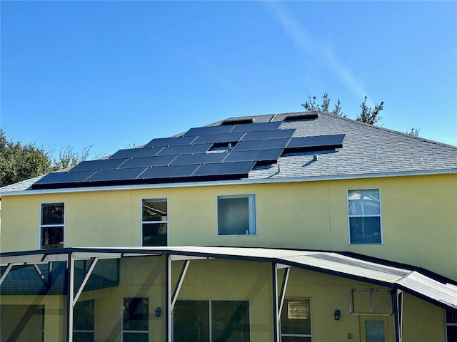 8520 La Isla Dr, Kissimmee, FL 34747 - back of house with roof with shingles, roof mounted solar panels, and stucco siding