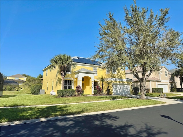 8520 La Isla Dr, Kissimmee, FL 34747 - mediterranean / spanish house featuring stucco siding, an attached garage, roof mounted solar panels, and a front lawn