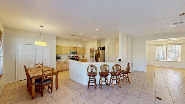 8520 La Isla Dr, Kissimmee, FL 34747 - kitchen with appliances with stainless steel finishes, light tile patterned flooring, a textured ceiling, light brown cabinetry, and a ceiling fan