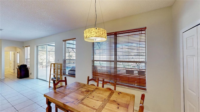8520 La Isla Dr, Kissimmee, FL 34747 - dining space with arched walkways, a textured ceiling, light tile patterned floors, and baseboards