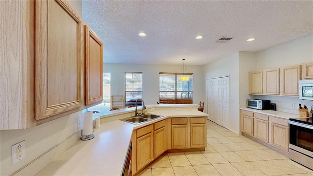 8520 La Isla Dr, Kissimmee, FL 34747 - kitchen with appliances with stainless steel finishes, a sink, a peninsula, light brown cabinetry, and a textured ceiling