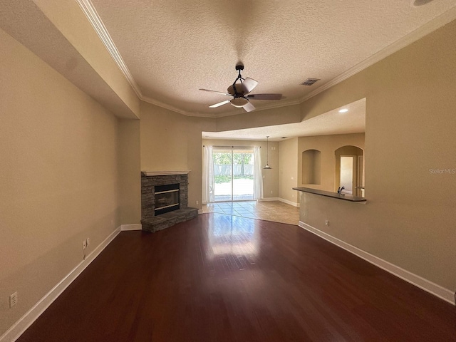 2585 Woodside Ridge Dr, Apopka, FL 32712 - unfurnished living room with ceiling fan, dark wood-style flooring, baseboards, a stone fireplace, and crown molding