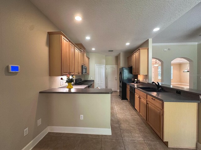 2585 Woodside Ridge Dr, Apopka, FL 32712 - kitchen featuring a sink, dark countertops, a peninsula, arched walkways, and a textured ceiling