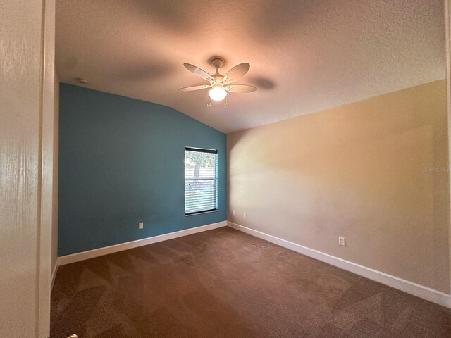 2585 Woodside Ridge Dr, Apopka, FL 32712 - empty room featuring a ceiling fan, vaulted ceiling, dark colored carpet, baseboards, and a textured ceiling