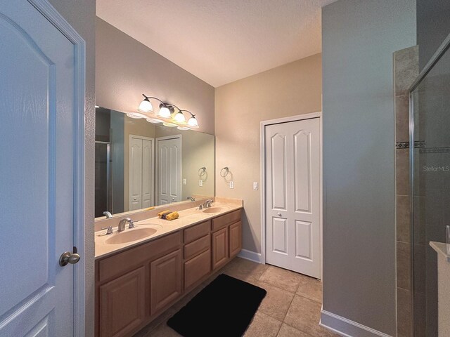 2585 Woodside Ridge Dr, Apopka, FL 32712 - bathroom featuring double vanity, tile patterned floors, tiled shower, and baseboards