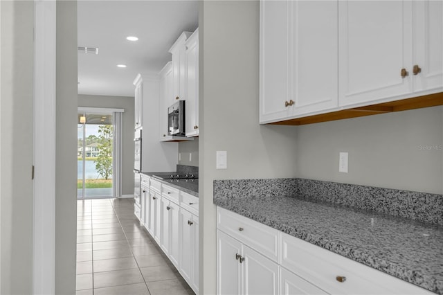 3137 Marine Grass Dr, Wimauma, FL 33598 - kitchen with white cabinetry, light stone countertops, light tile patterned floors, recessed lighting, and stainless steel microwave