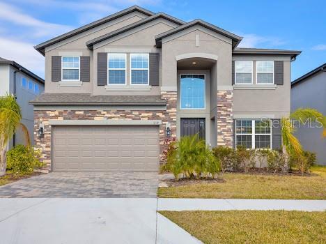 3137 Marine Grass Dr, Wimauma, FL 33598 - view of front of property with stucco siding, stone siding, driveway, and an attached garage