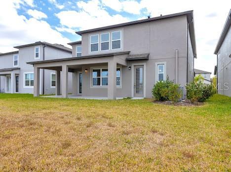 3137 Marine Grass Dr, Wimauma, FL 33598 - back of property with stucco siding and a lawn