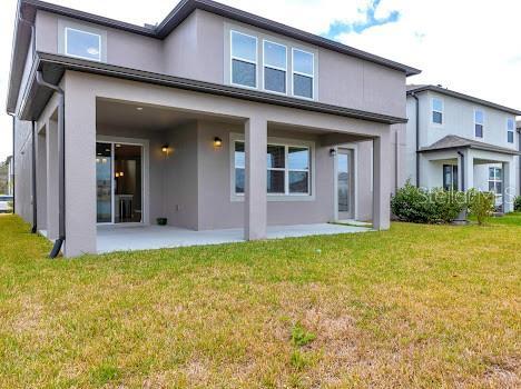 3137 Marine Grass Dr, Wimauma, FL 33598 - back of property featuring stucco siding, a patio area, and a lawn