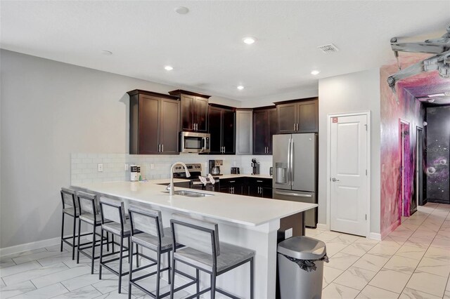1533 Flange Dr, Davenport, FL 33896 - kitchen with appliances with stainless steel finishes, a sink, light marble finish flooring, a kitchen breakfast bar, and a peninsula