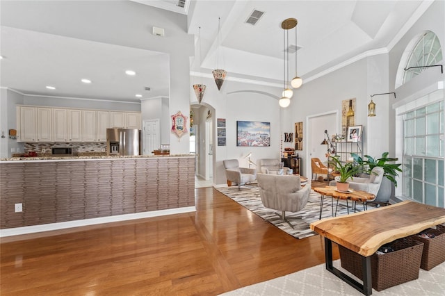 13108 Lakeshore Grove Dr, Winter Garden, FL 34787 - living area featuring crown molding, light wood-type flooring, arched walkways, a high ceiling, and a tray ceiling
