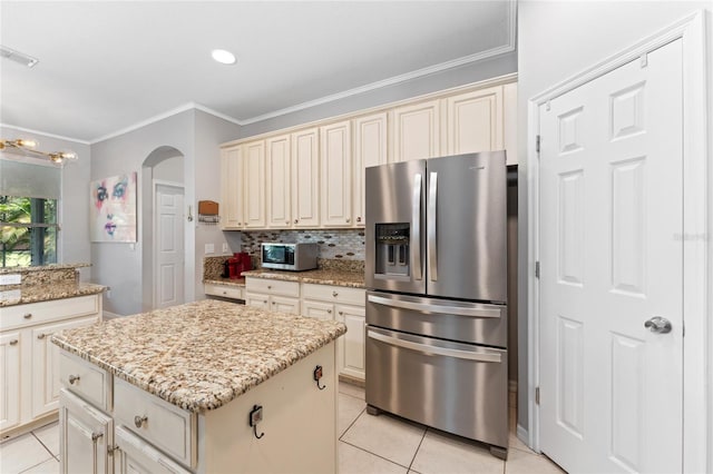 13108 Lakeshore Grove Dr, Winter Garden, FL 34787 - kitchen with appliances with stainless steel finishes, cream cabinets, light tile patterned floors, ornamental molding, and a center island