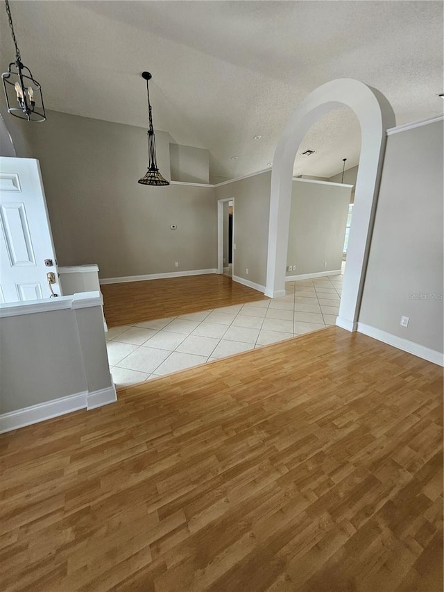 1710 Canoe Creek Rd, Oviedo, FL 32766 - unfurnished dining area with lofted ceiling, light wood-style floors, arched walkways, a textured ceiling, and baseboards