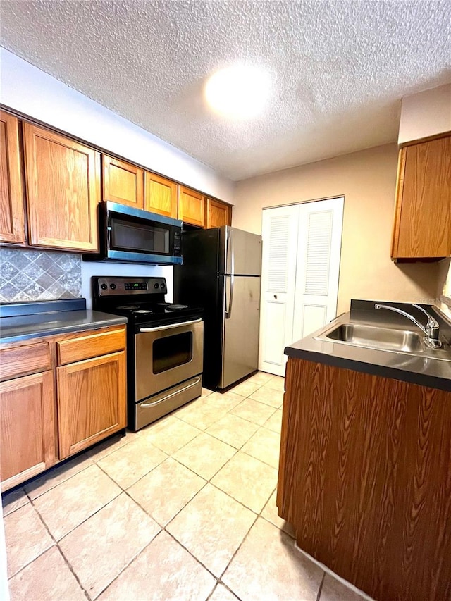 1057 S Hiawassee Rd Unit 1913, Orlando, FL 32835 - kitchen with appliances with stainless steel finishes, a sink, dark countertops, brown cabinets, and decorative backsplash