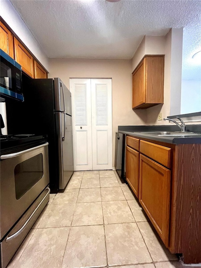 1057 S Hiawassee Rd Unit 1913, Orlando, FL 32835 - kitchen featuring brown cabinetry, a textured ceiling, dark countertops, and light tile patterned floors