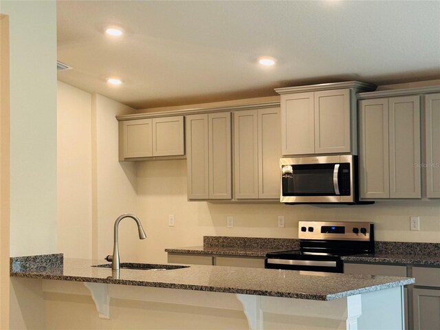 4326 Sagefield Dr, Harmony, FL 34773 - kitchen with stainless steel appliances, gray cabinetry, a breakfast bar, a sink, and recessed lighting