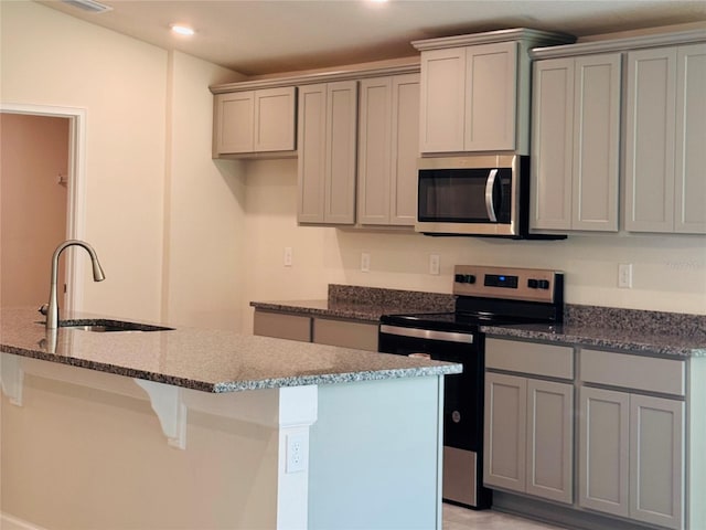 4326 Sagefield Dr, Harmony, FL 34773 - kitchen with a sink, appliances with stainless steel finishes, gray cabinets, dark stone counters, and recessed lighting