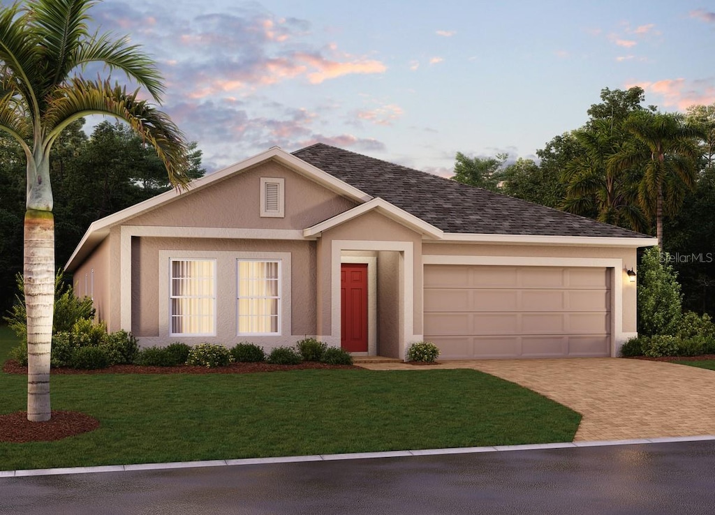 447 Lemongrass Rd, Minneola, FL 34715 - view of front of house featuring an attached garage, decorative driveway, stucco siding, and a front yard