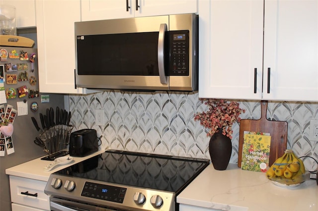 3044 S Oakland Forest Dr Unit 2403, Oakland Park, FL 33309 - kitchen with stainless steel appliances, white cabinetry, backsplash, and light stone countertops