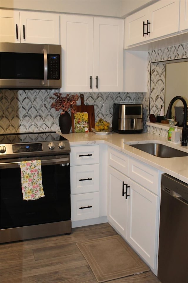 3044 S Oakland Forest Dr Unit 2403, Oakland Park, FL 33309 - kitchen with stainless steel appliances, a sink, light countertops, white cabinets, and decorative backsplash
