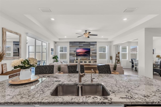 10815 Laxer Cay Loop, San Antonio, FL 33576 - kitchen featuring a sink, open floor plan, a ceiling fan, light stone counters, and healthy amount of natural light