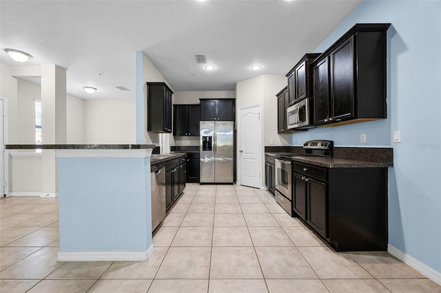 2193 Betsy Ross Ln, Saint Cloud, FL 34769 - kitchen featuring appliances with stainless steel finishes, dark countertops, light tile patterned flooring, baseboards, and dark cabinetry