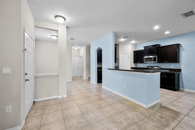 2193 Betsy Ross Ln, Saint Cloud, FL 34769 - kitchen featuring stainless steel microwave, dark countertops, light tile patterned floors, a textured ceiling, and baseboards