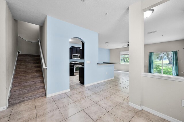 2193 Betsy Ross Ln, Saint Cloud, FL 34769 - unfurnished room with light tile patterned floors, ceiling fan, baseboards, arched walkways, and a textured ceiling