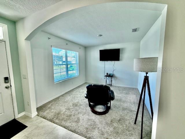 6780 Coral Berry Dr, Mount Dora, FL 32757 - interior space with carpet floors, arched walkways, a textured ceiling, baseboards, and tile patterned floors