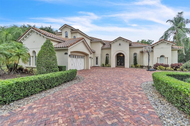 9729 Lake Hugh Dr, Gotha, FL 34734 - mediterranean / spanish house with stucco siding, decorative driveway, a garage, french doors, and a tiled roof