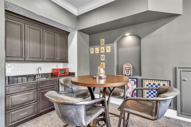 9729 Lake Hugh Dr, Gotha, FL 34734 - dining area with crown molding, light carpet, bar with sink, and arched walkways